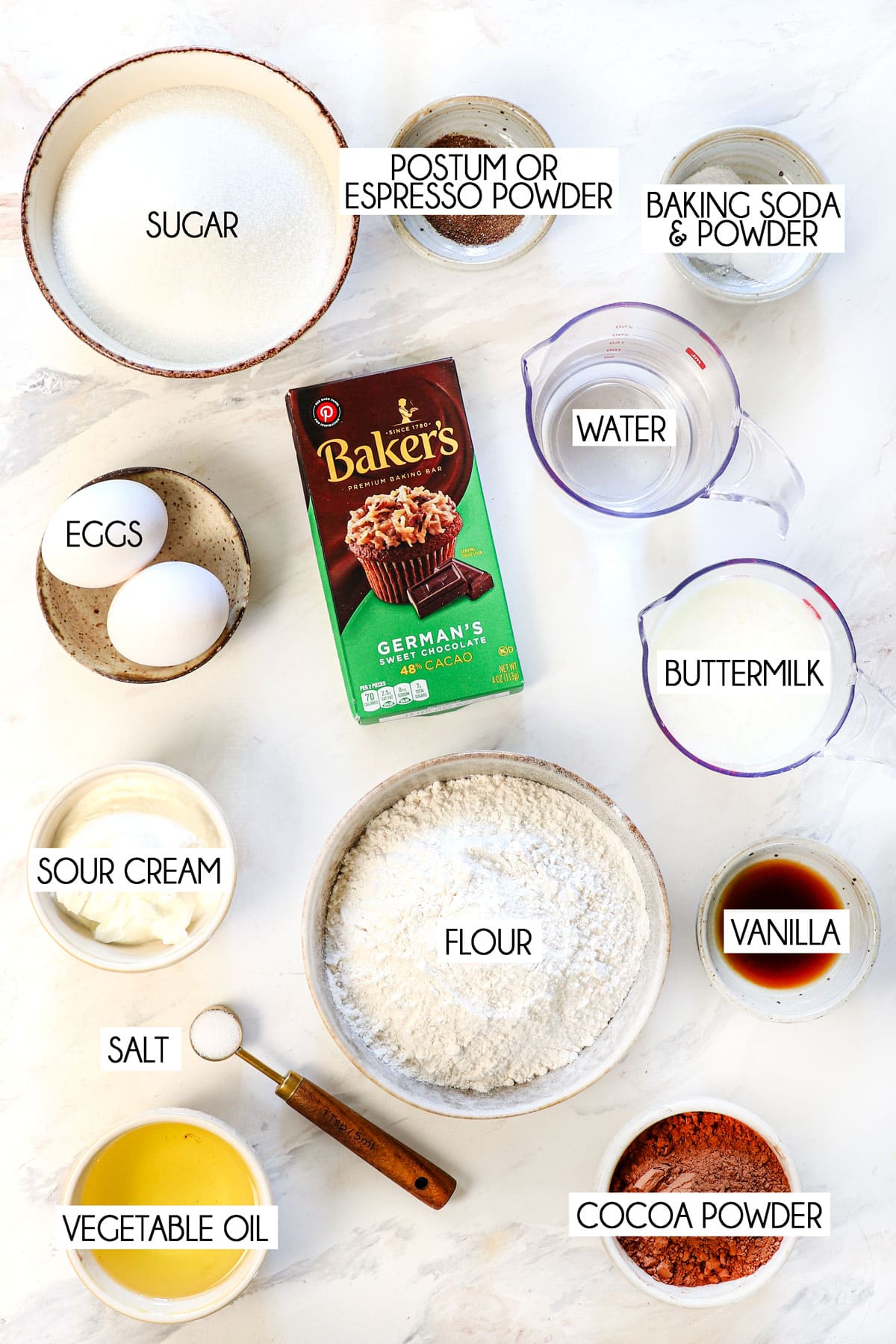 Top view of German Chocolate Cake Ingredients: Baker’s German sweet chocolate (finely chopped), hot water, all-purpose flour, dark unsweetened cocoa powder, baking soda, baking powder, espresso powder (optional but recommended for extra depth), granulated sugar, salt, buttermilk at room temperature, full-fat sour cream at room temperature, vegetable oil, eggs at room temperature, and pure vanilla extract.