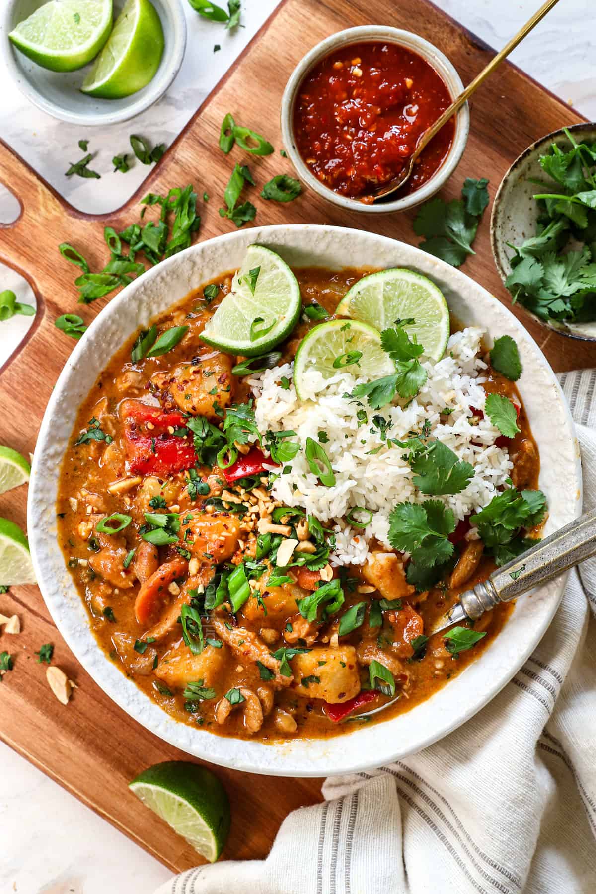 showing how to serve Thai massaman curry recipe in a bowl being served with rice, cilantro, lime juice, and peanuts