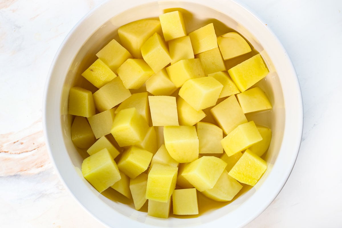 showing how to make massaman curry by cooking the potatoes in the microwave safe dish