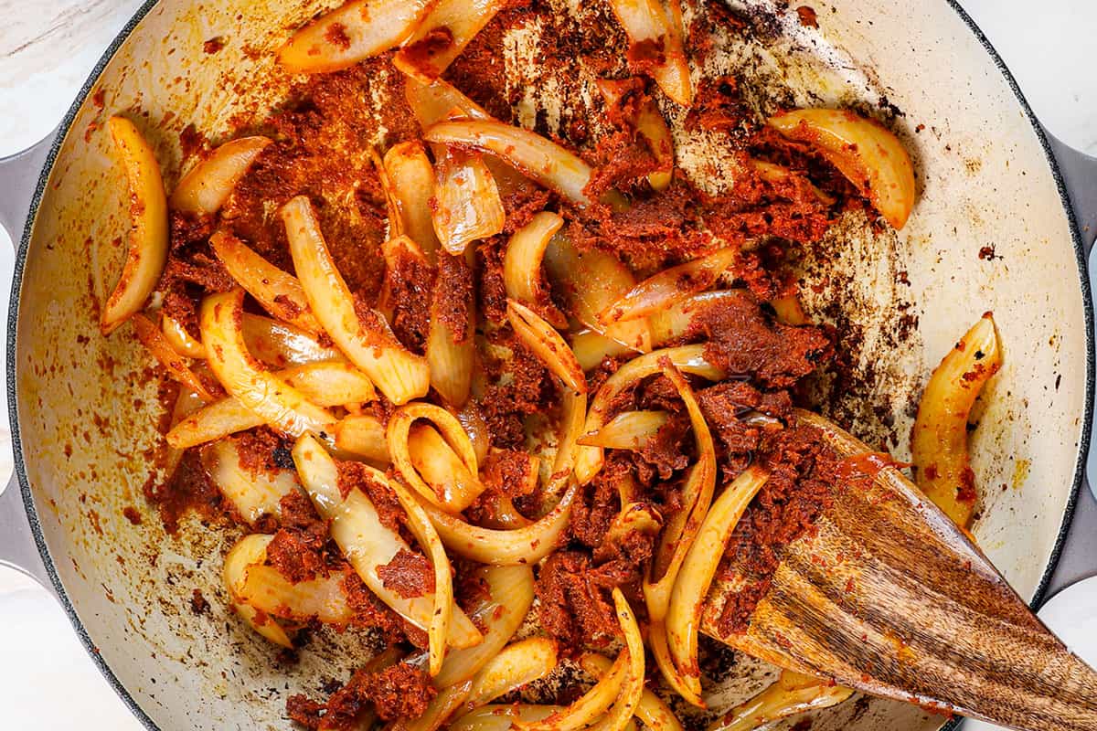 showing how to make massaman curry by blooming the curry in oil with the onions