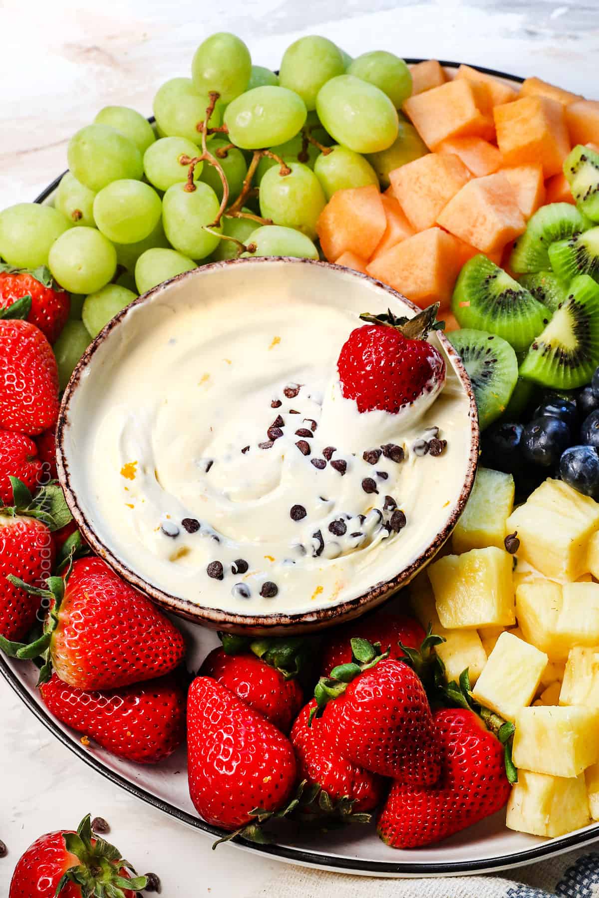 showing how to serve cream cheese fruit dip garnished with chocolate chips and orange zest