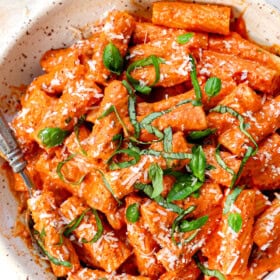 top view of pink sauce recipe being served with pasta in a bowl garnished with Parmesan and basil