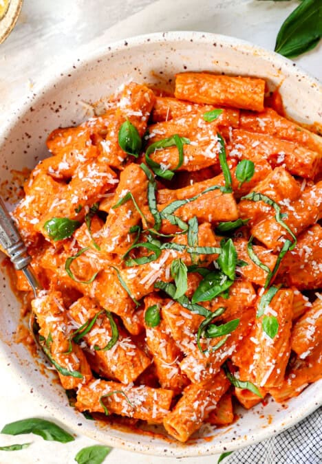 top view of pink sauce recipe being served with pasta in a bowl garnished with Parmesan and basil