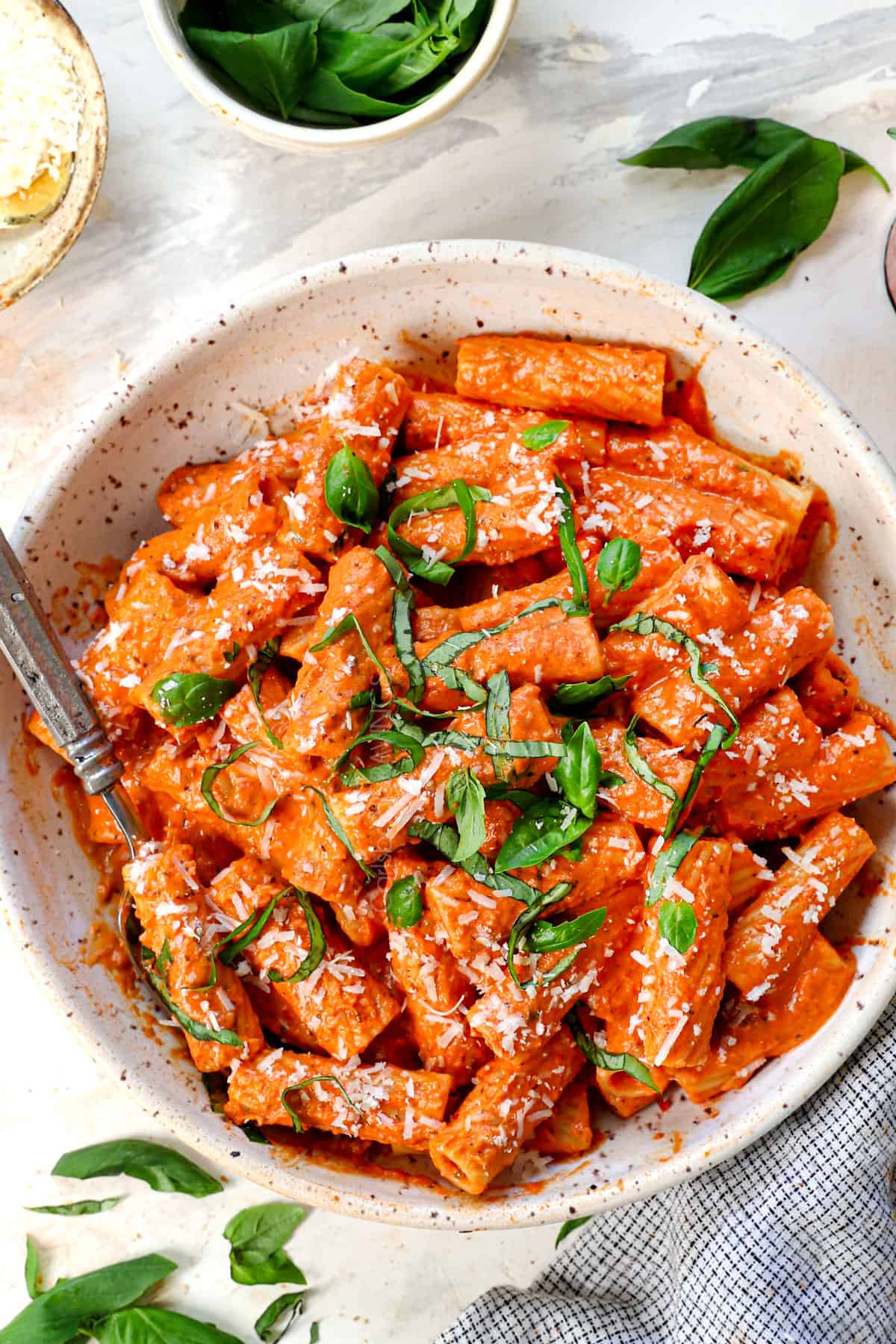 top view of pink sauce recipe being served with pasta in a bowl garnished with Parmesan and basil
