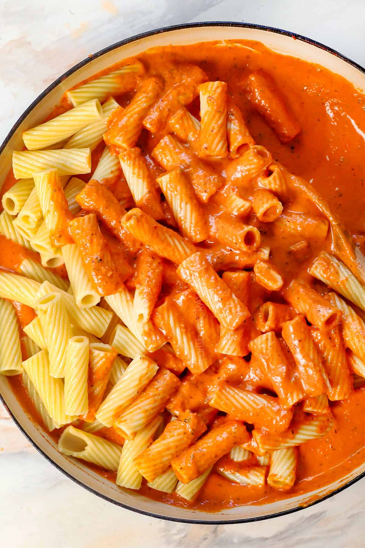 showing how to make pink sauce by stirring in the pasta to coat in the sauce