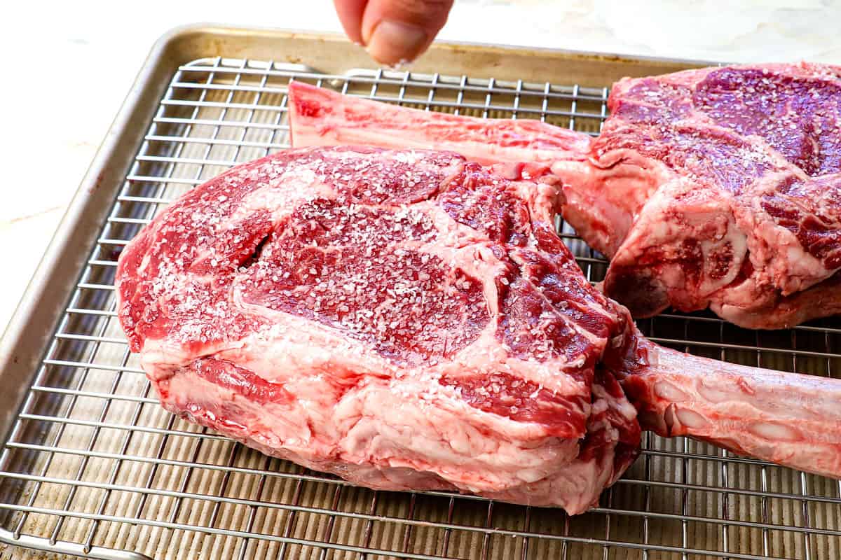 showing how to cook tomahawk steak by seasoning with kosher salt and freshly cracked pepper, then allowing to dry brine