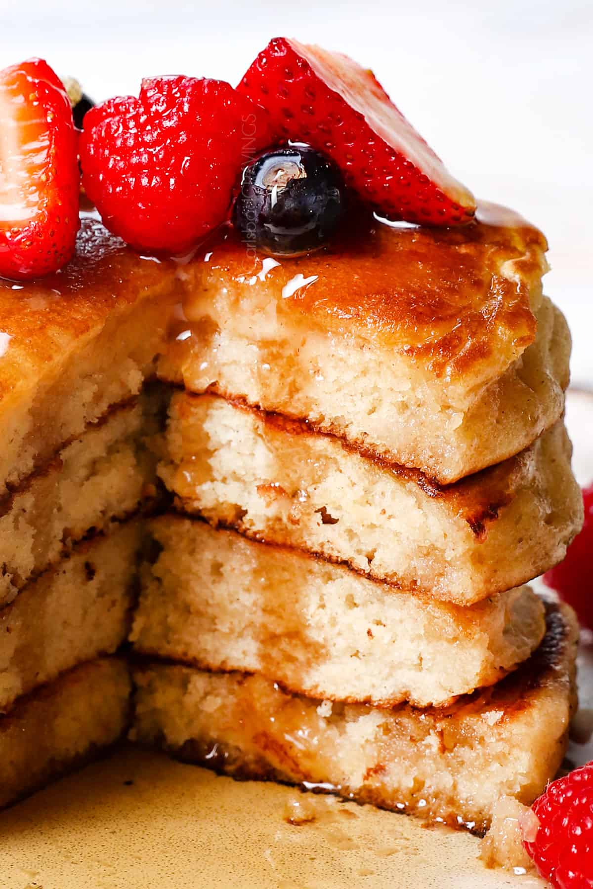 up close of homemade fluffy pancakes with a few bites missing showing how fluffy the inside of the pancakes are
