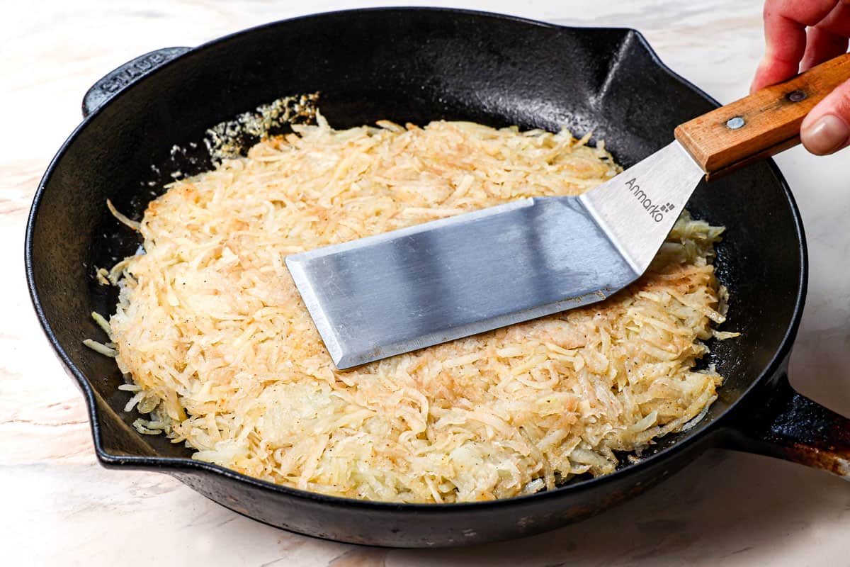 showing how to make hash browns by flattening the potatoes into a single layer in the skillet
