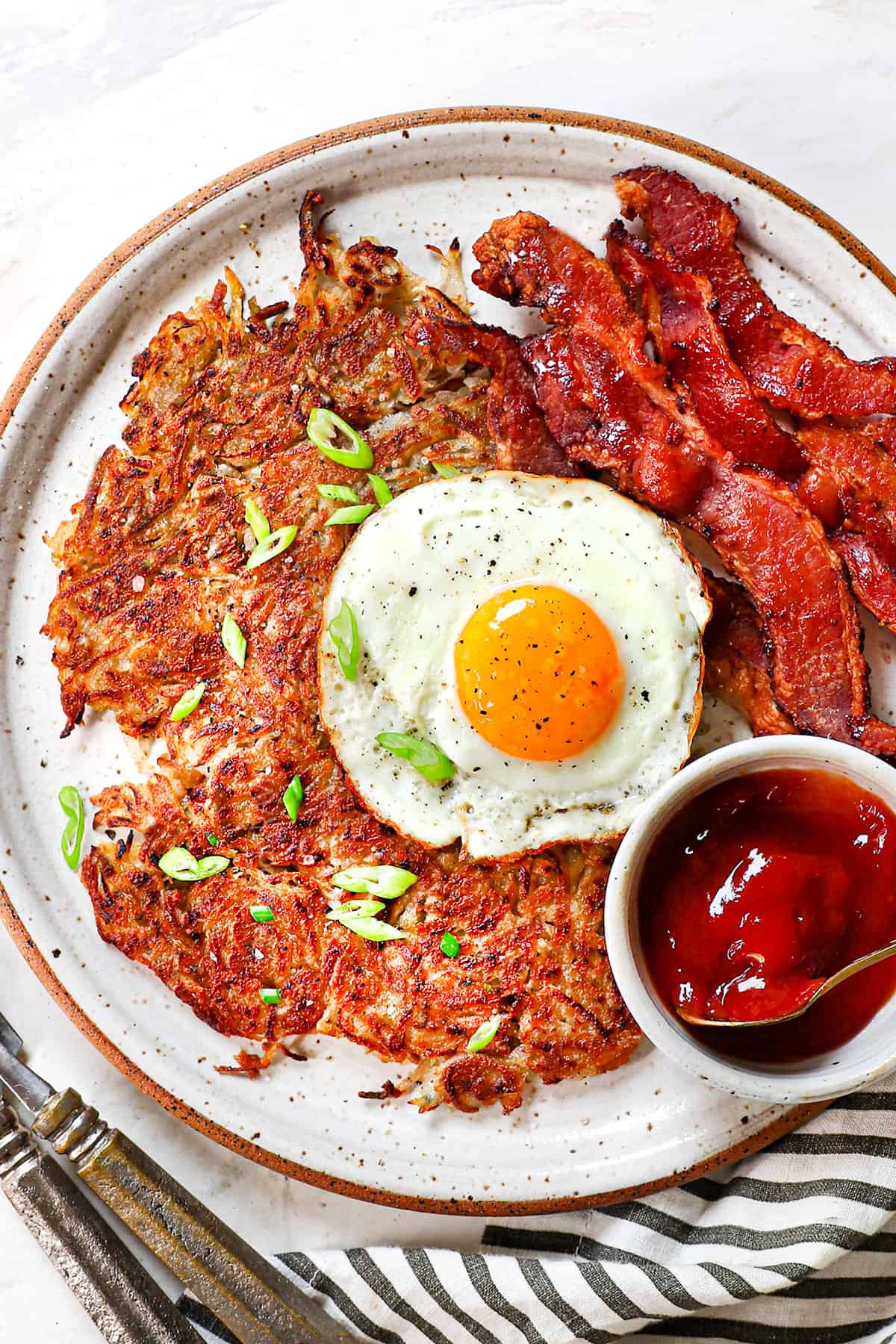 top view showing how to serve homemade hash browns with egg and bacon, garnished by green onions