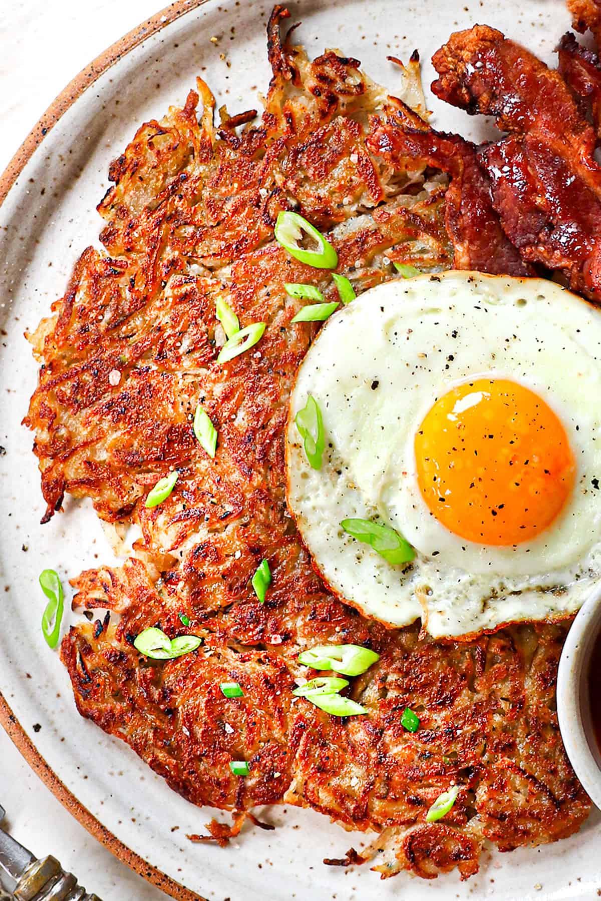 top view showing how to serve homemade hash browns with egg and bacon, garnished by green onions