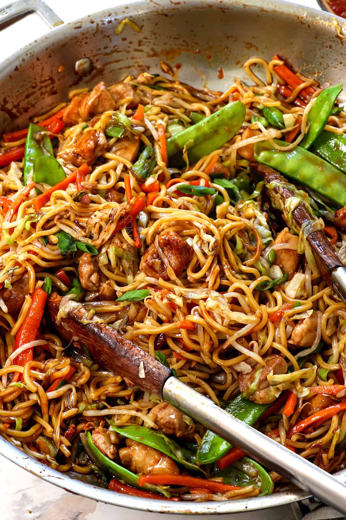 lo mein noodles being tossed with tongs