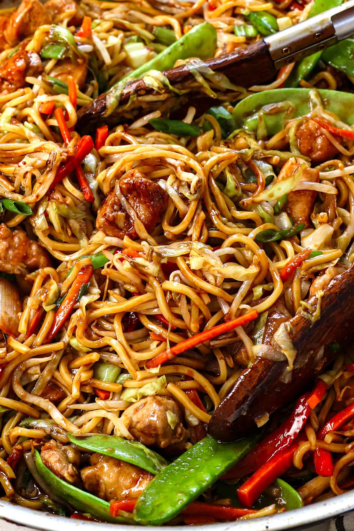 showing how to make lo mein by tossing the sprouts and chicken together with the noodles