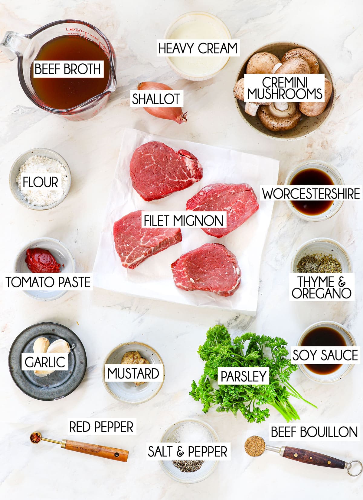 top view of Steak Diane ingredients: filet mignon, beef broth, heavy cream, garlic, shallots, parsley, mustard, Worcestershire sauce, thyme, oregano, cremini mushrooms, salt and pepper