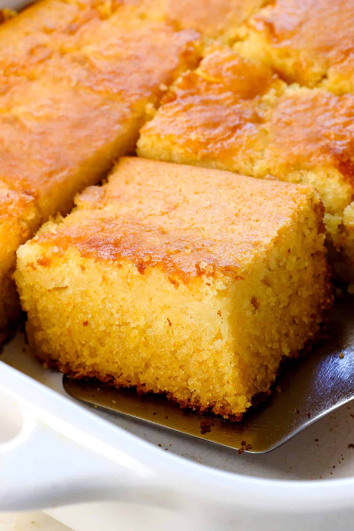 a slice of homemade cornbread recipe in a 9x13 pan with a golden top