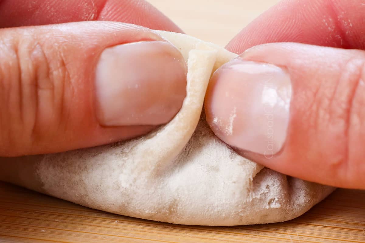 showing how to fold gyoza by creating pleats, then pressing them back into the dough to seal