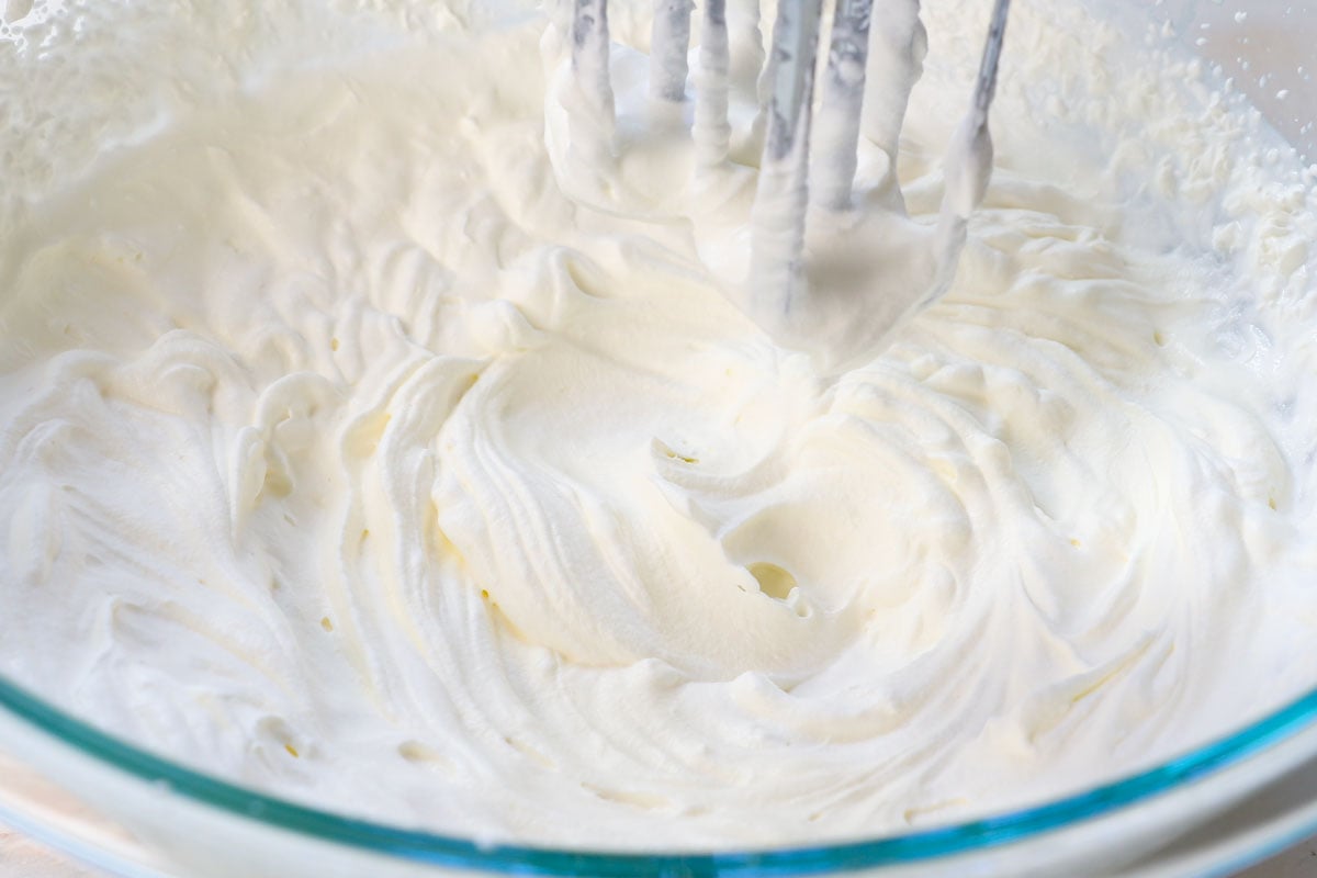 showing how to make no bake cheesecake by whipping the heavy cream to stiff peaks