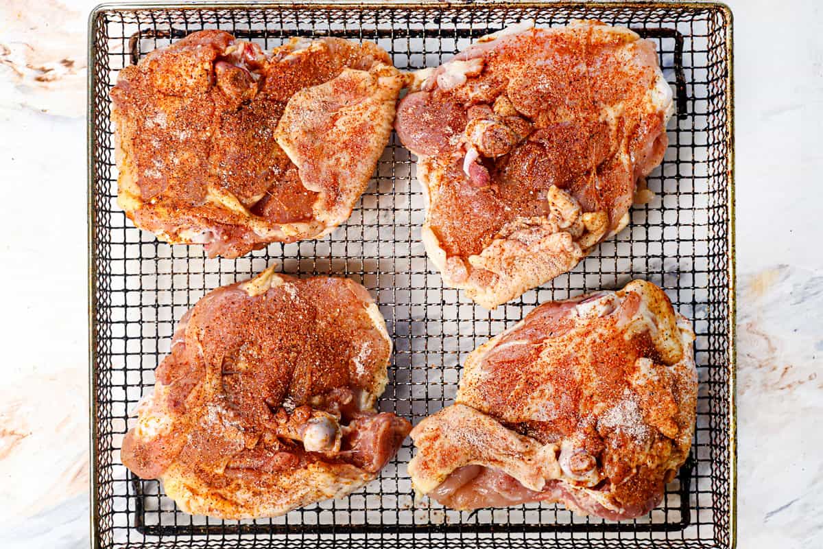 showing how to cook chicken thighs in air fryer by cooking skin side down in the air fryer before flipping halfway through