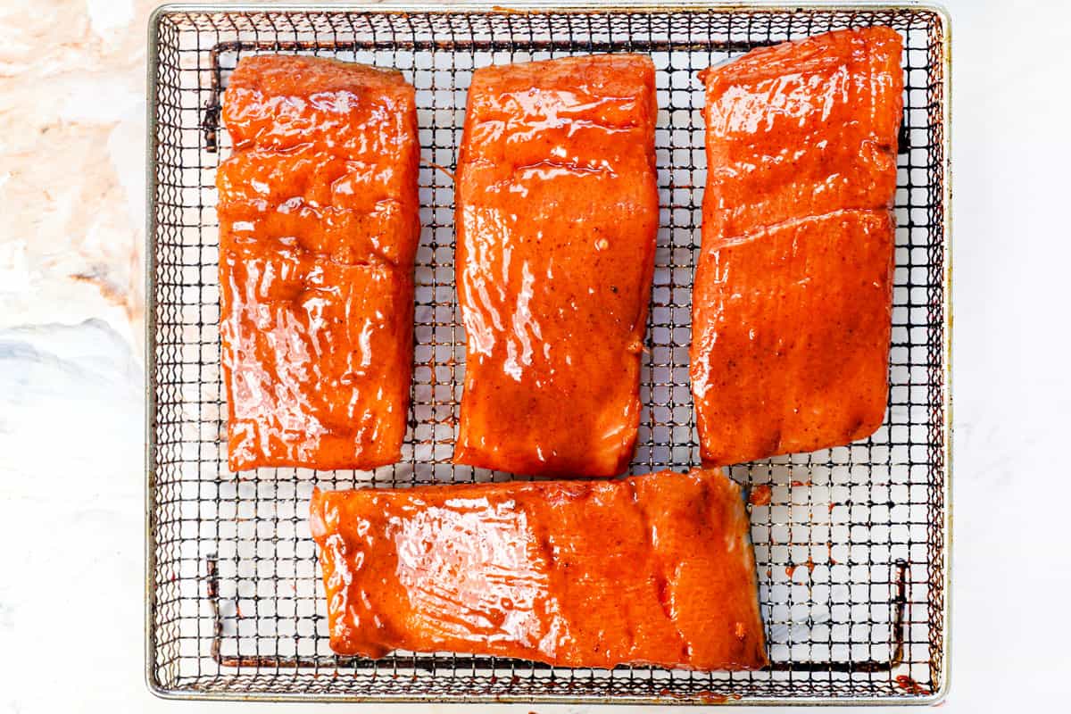 showing how to air fry salmon by placing in the air fryer basket and air frying until cooked