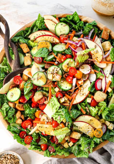 toss salad in a bowl with wood tongs showing how to serve