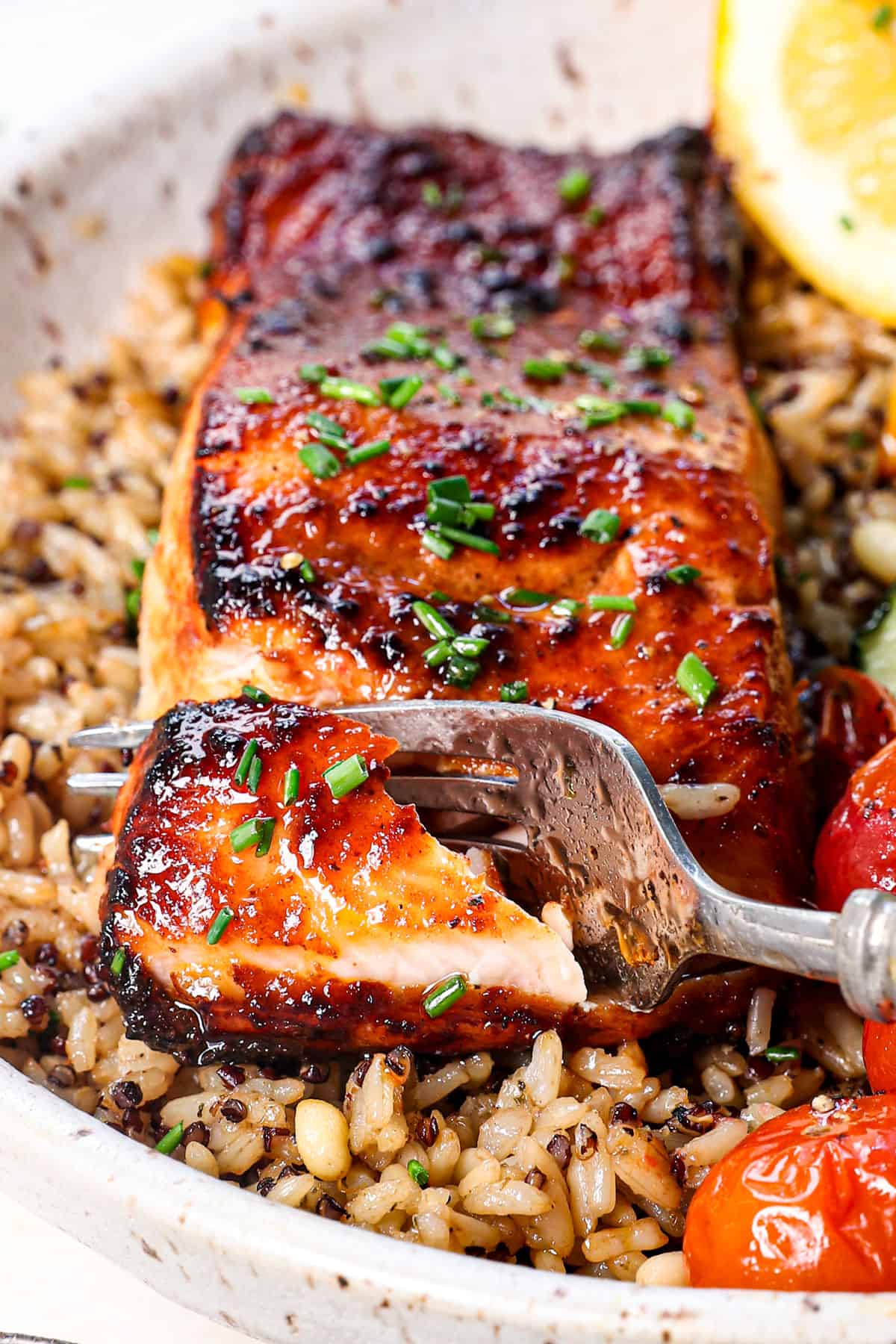 a fork biting into salmon air fryer recipe garnished with parsley and chives