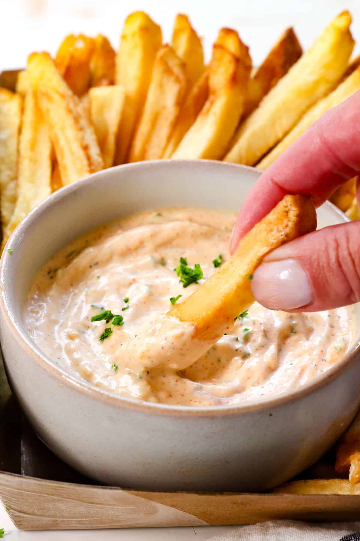 dipping a French fry into Garlic aioli recipe to show how creamy it is