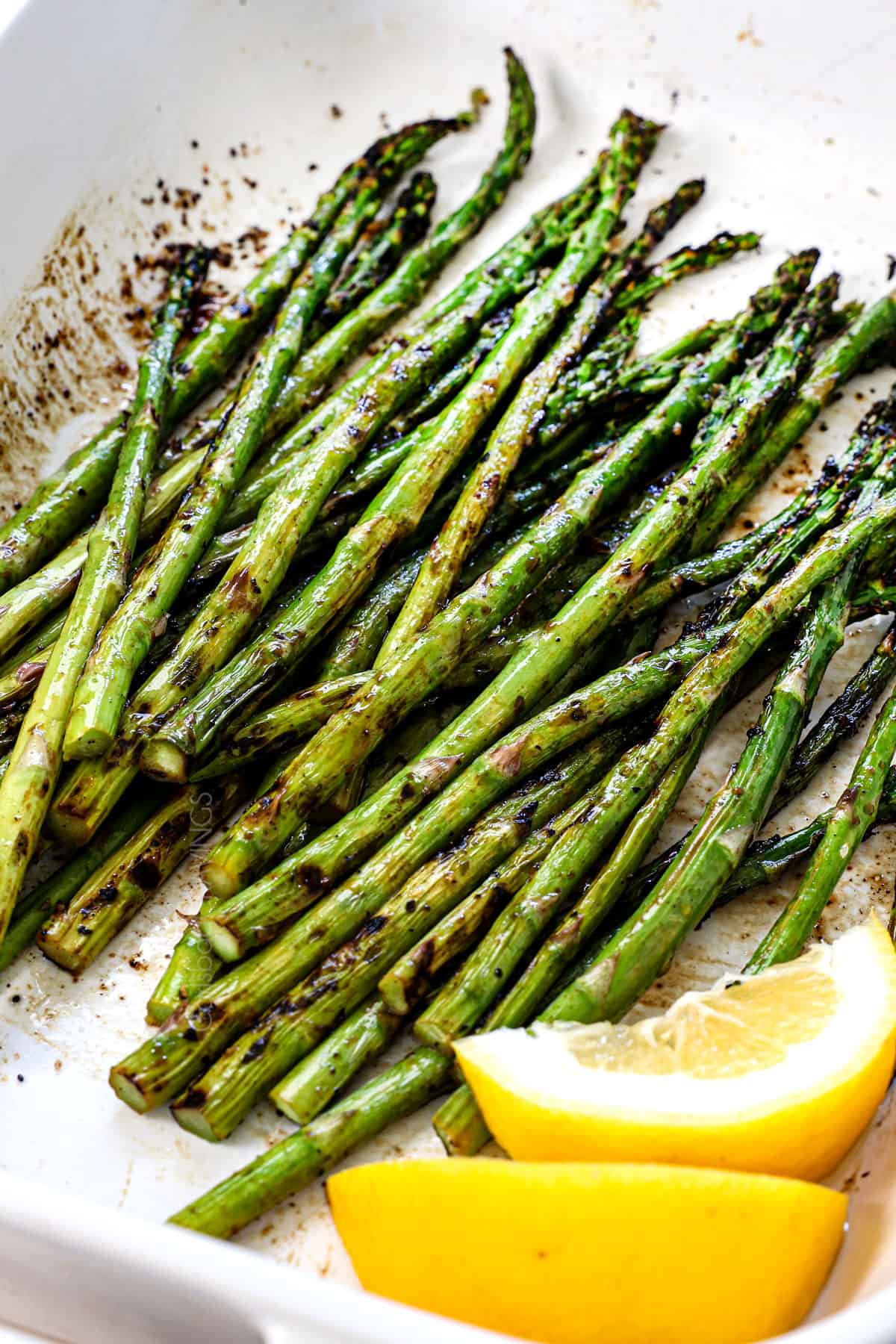 showing how to grill asparagus by rolling the cooked asparagus in balsamic after it's cooked