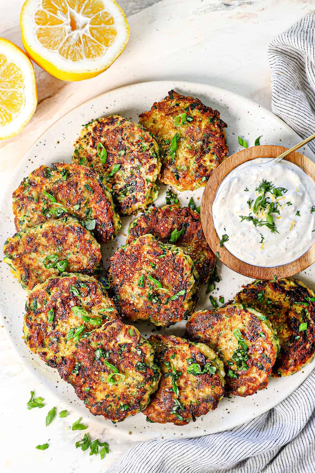 top view of serving zucchini fritters recipe on a platter with garlic sauce