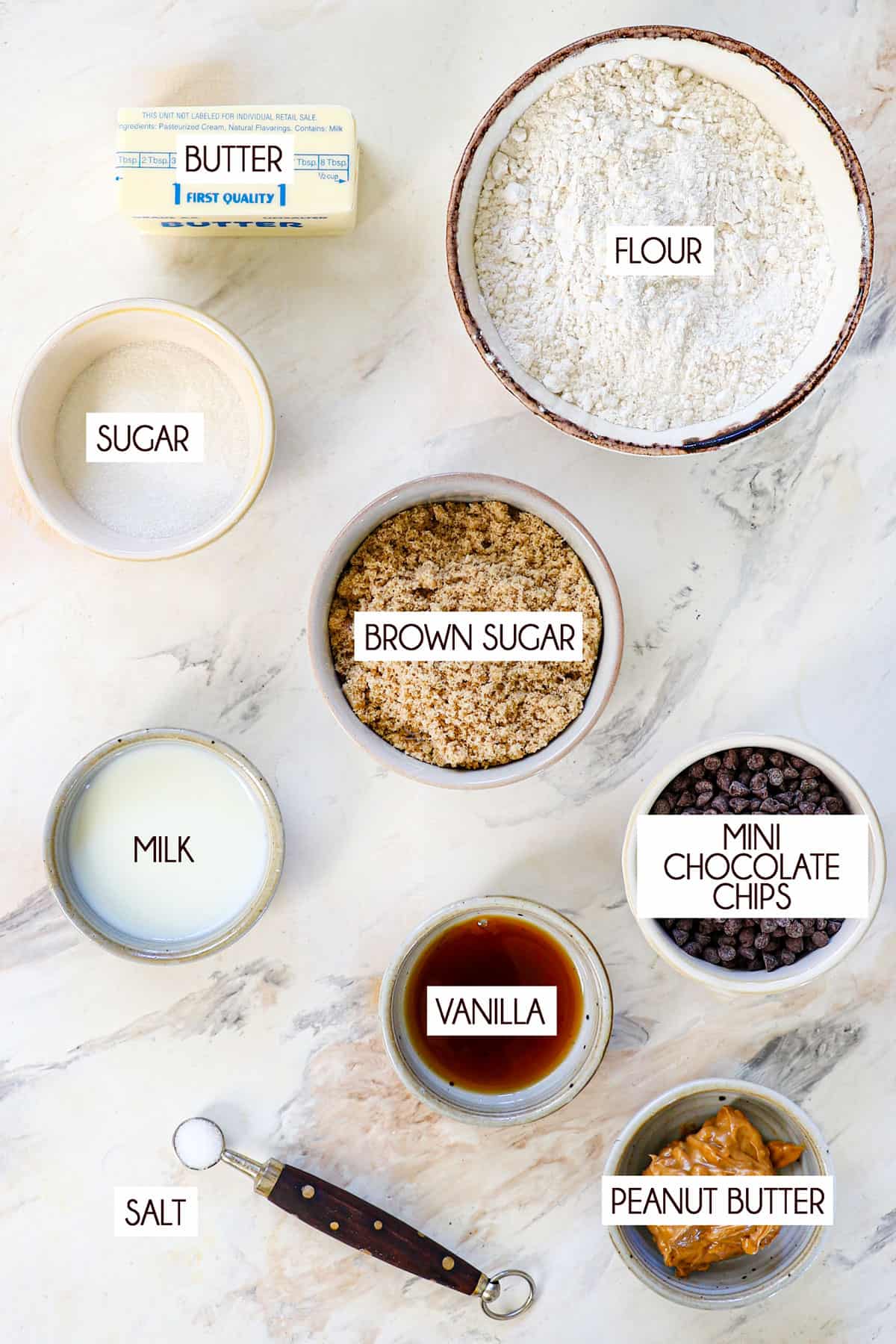 Top view of edible cookie dough ingredients: flour, granulated sugar, brown sugar, butter, salt, vanilla extract and mini chocolate chips