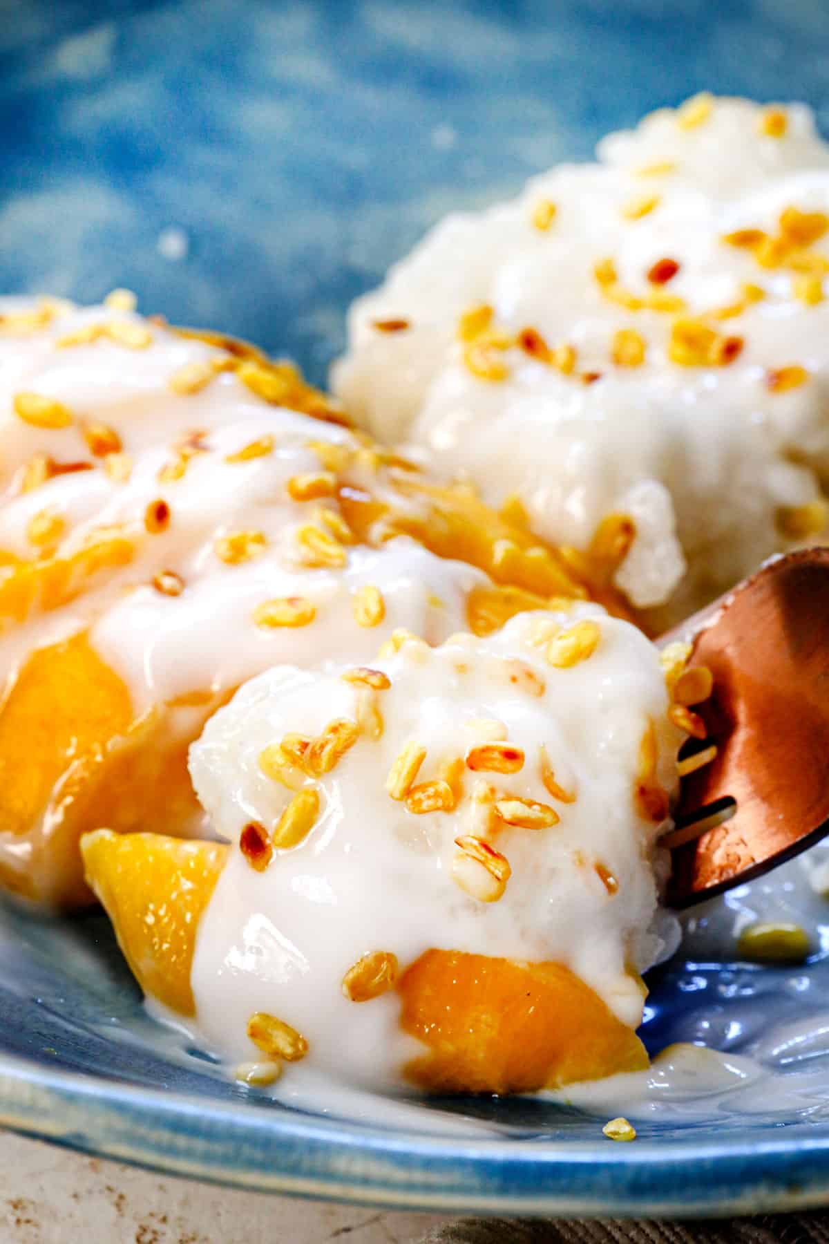 up close of taking a bite of sticky rice and mango with a fork showing the texture of the rice and consistency of the sauce