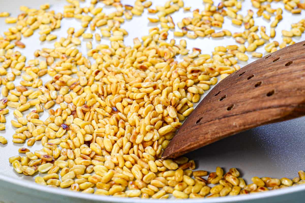 showing how to make mango sticky rice by toasting the mung beans in a skillet until golden