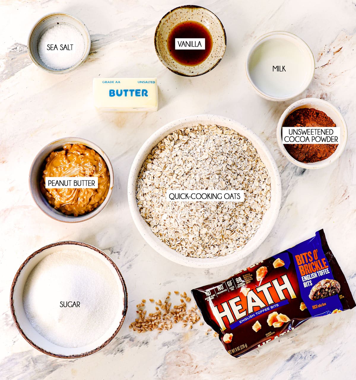 top view of no bake cookie ingredients: quick cooking oats, sugar, cocoa powder, peanut butter, butter, vanilla extract, milk and salt