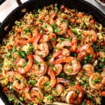 showing how to make shrimp fried rice by garnishing with green onions and seasoning to taste
