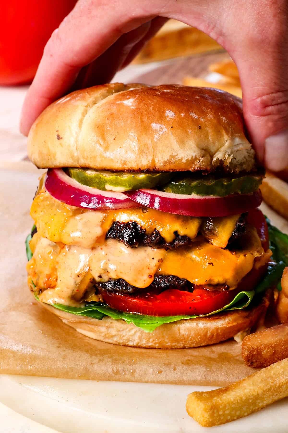 putting the top bun on a smash burger showing how to assemble