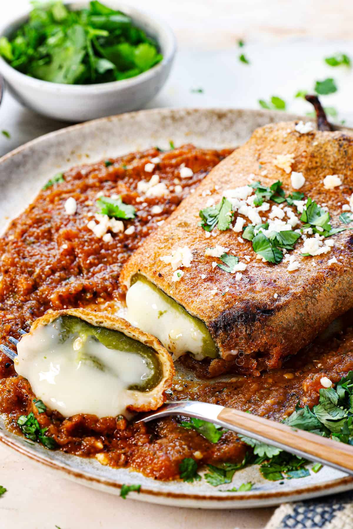 chille rellenos recipe with a bite taken out showing the melty cheese