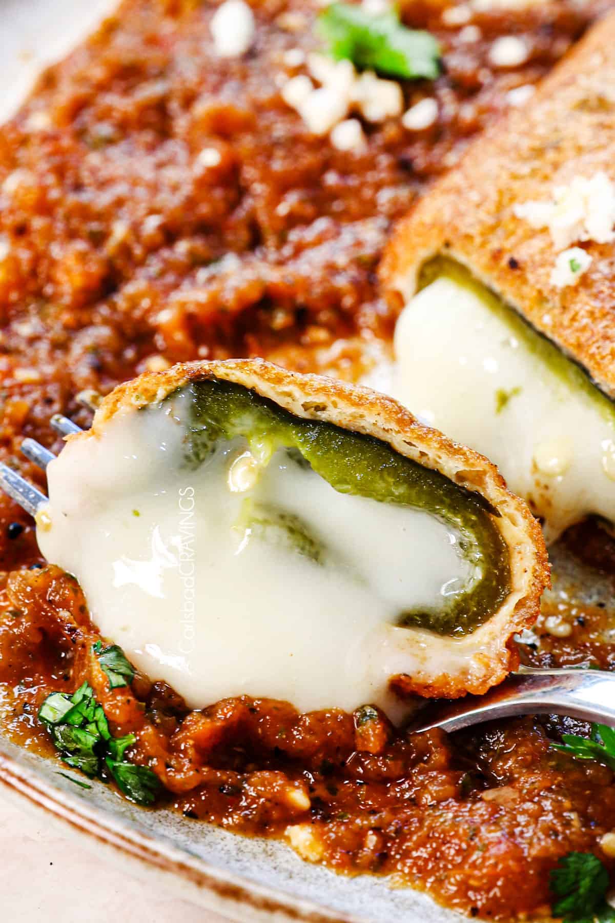 up close of a bite of chile rellenos showing they melty cheese and fried poblano