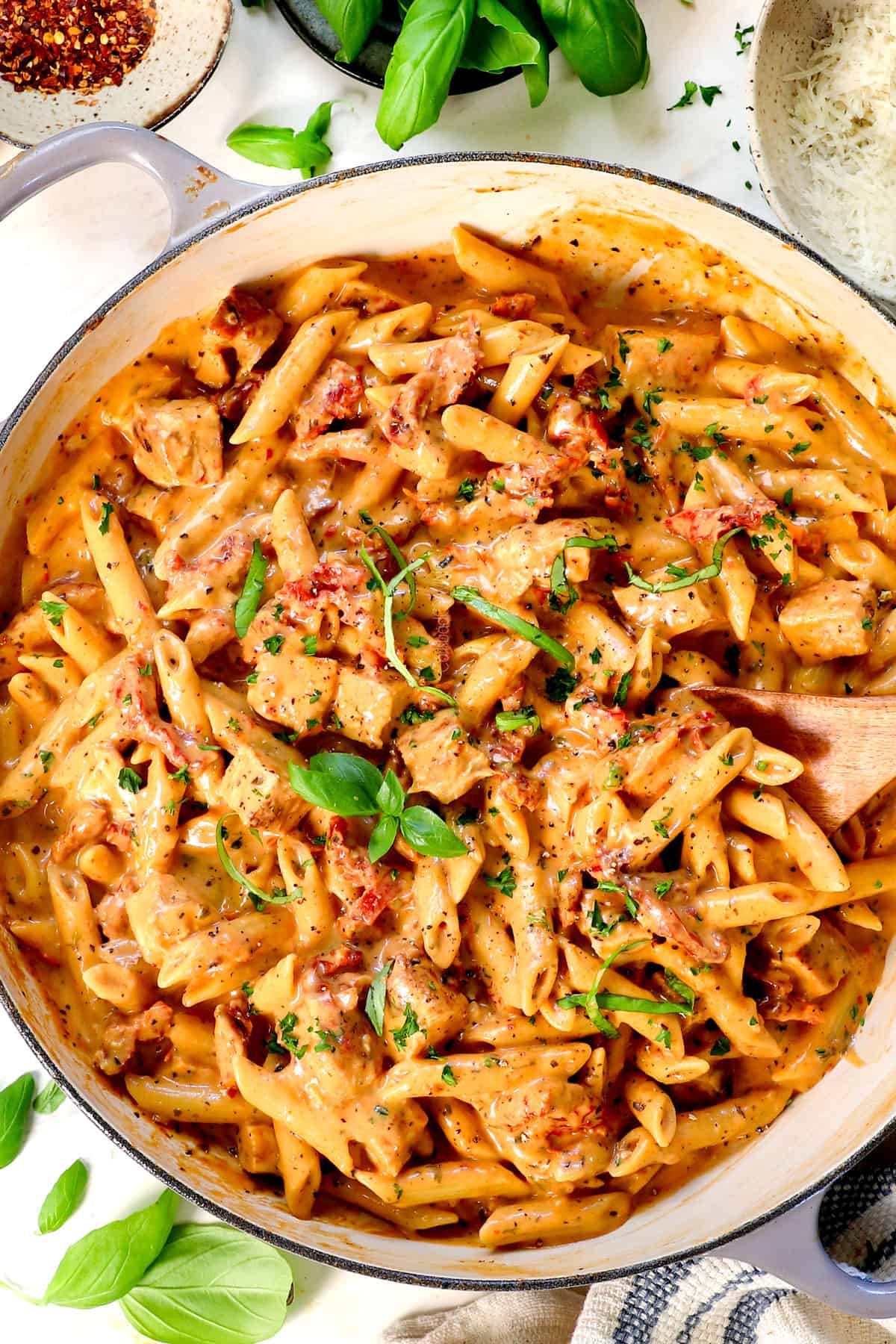 showing how to make marry me chicken by garnishing with fresh basil and parsley, salt, and pepper