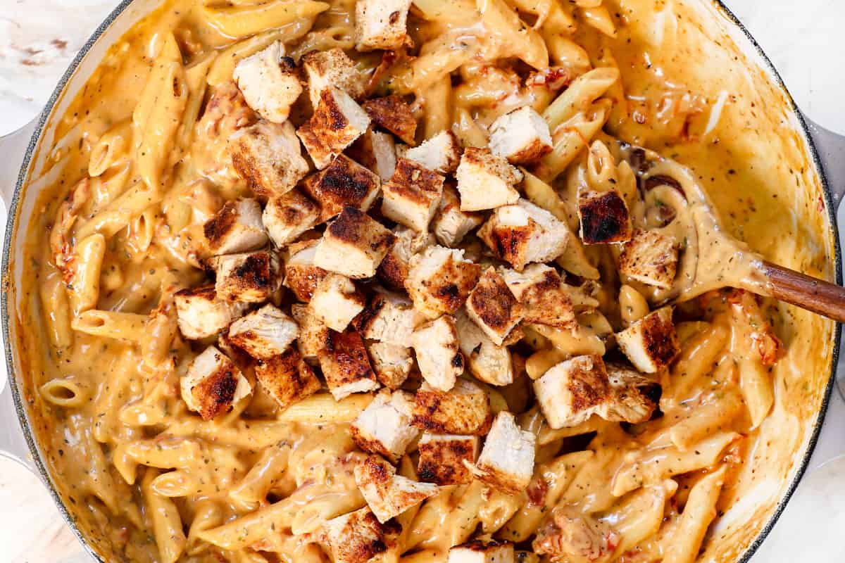 showing how to make Marry Me Chicken by stirring the pasta and chicken into the sauce