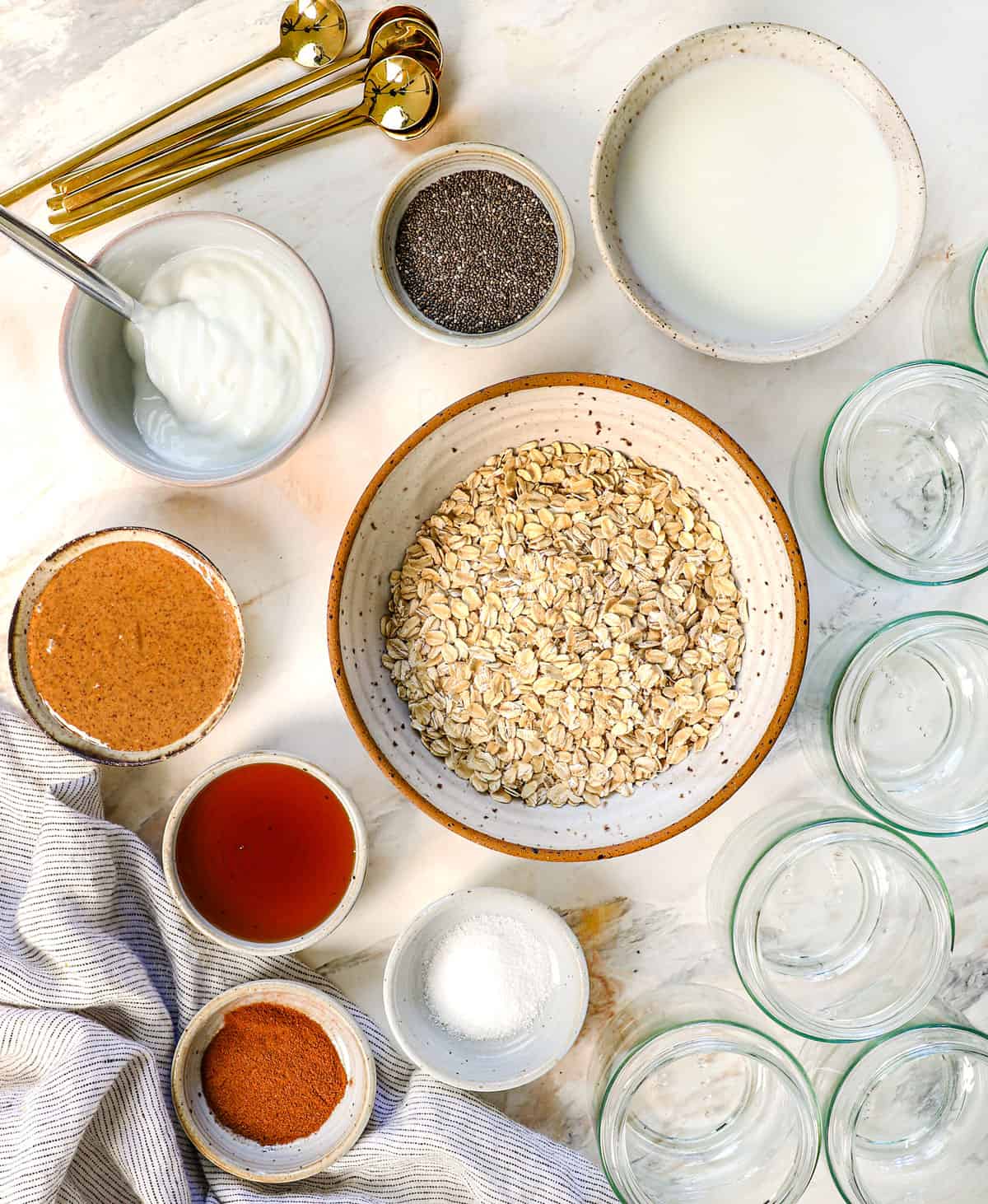 top view of overnight oats ingredients: rolled oats, Greek yogurt, maple, peanut butter, chia seeds, milk