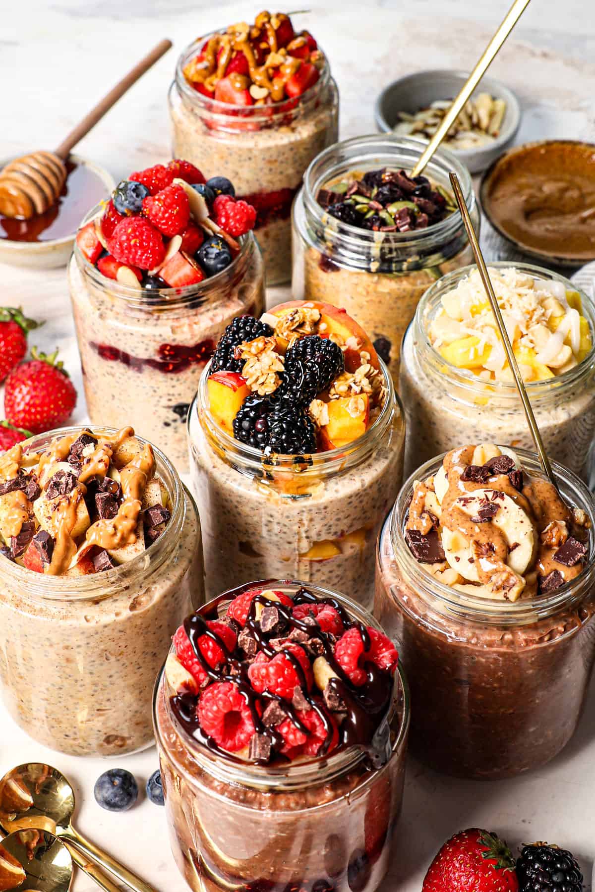 showing how to make overnight oats by diving the mixture into jars and topping nine different ways