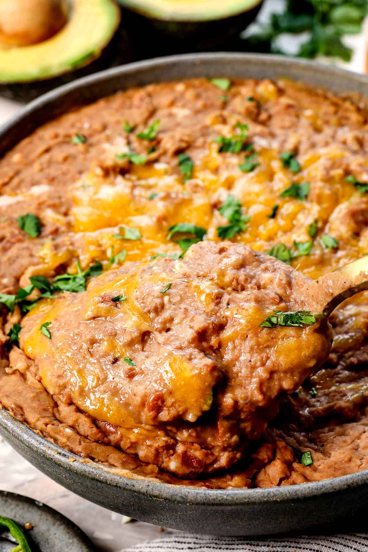 scooping up refried pinto beans with a spoon showing how creamy they are
