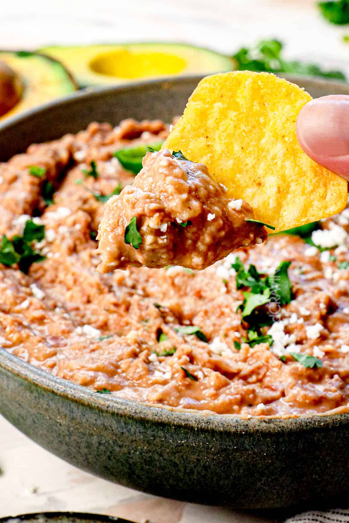 showing ways to serve refried beans recipe by dipping a chip into refried beans