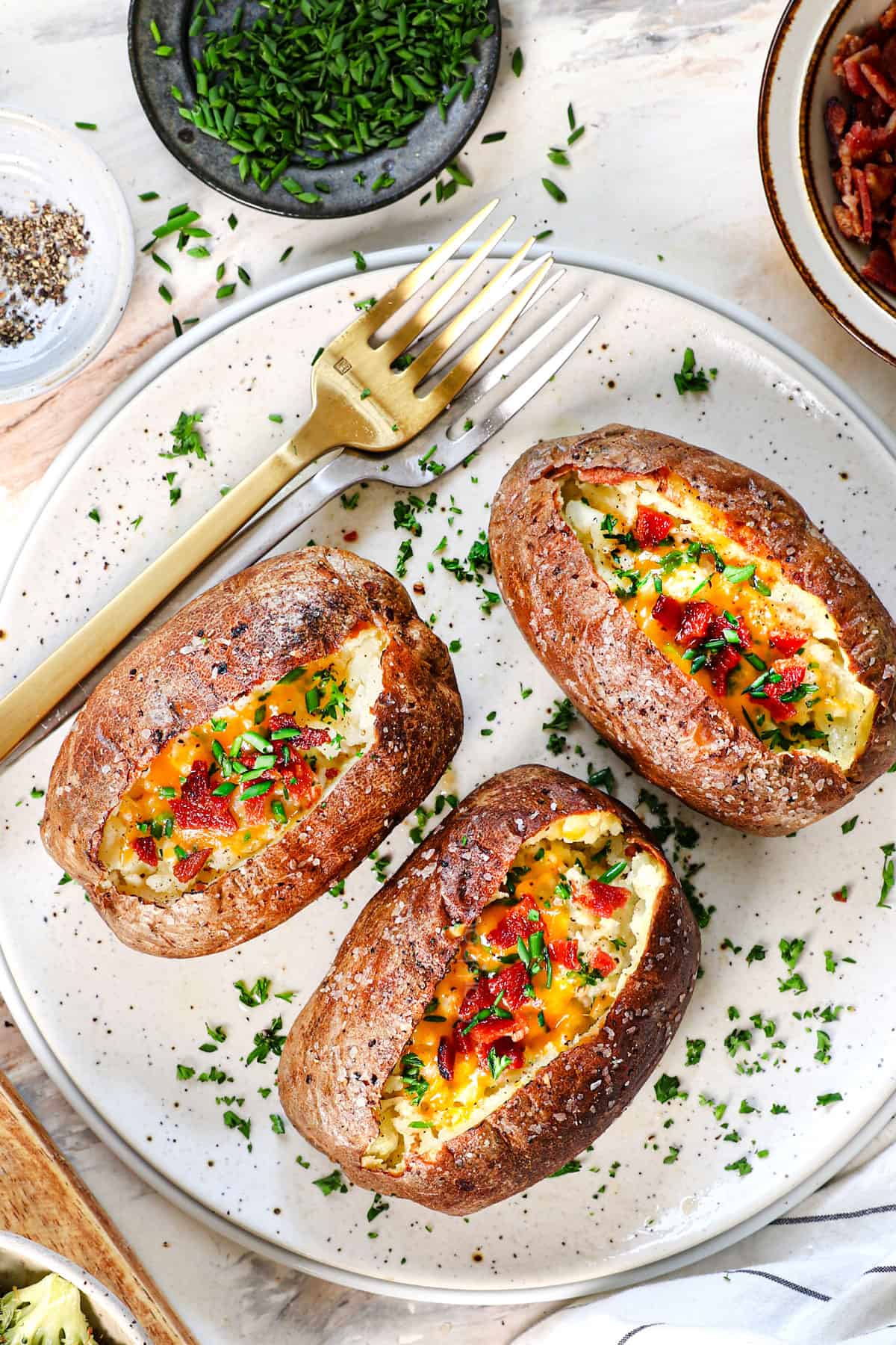 baked potato air fryer being served with cheese and bacon bits