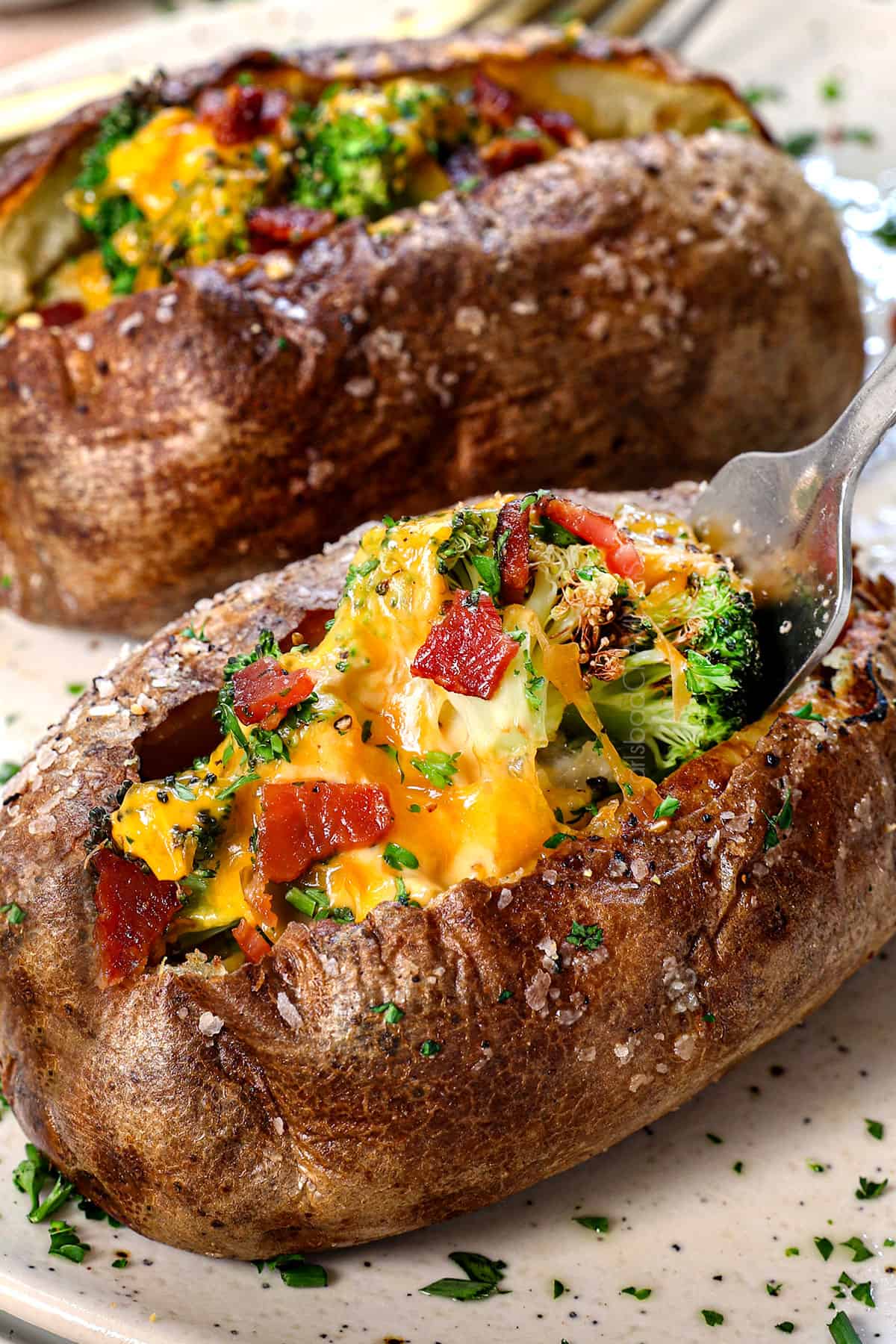taking a bite of baked potato in air fryer with cheese and broccoli