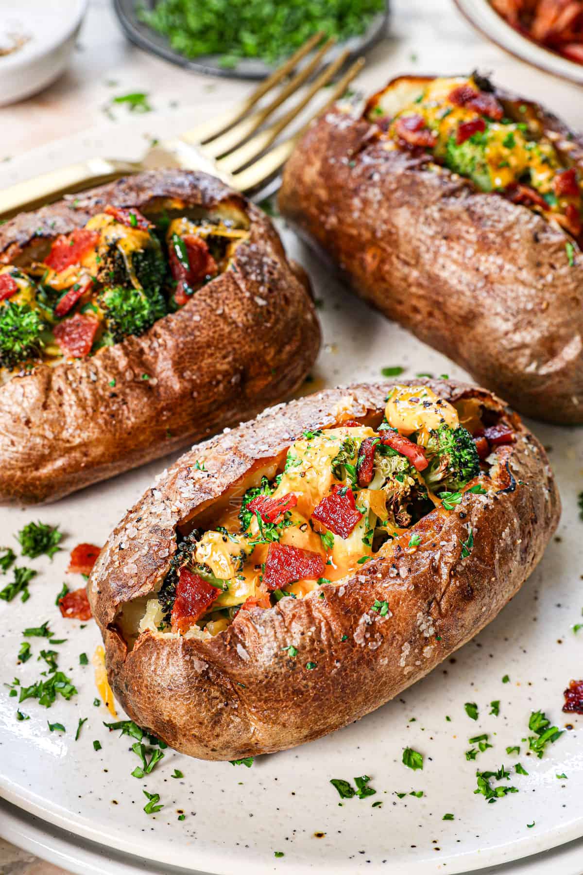 air fryer baked potatoes on a plate topped with cheese, broccoli and bacon