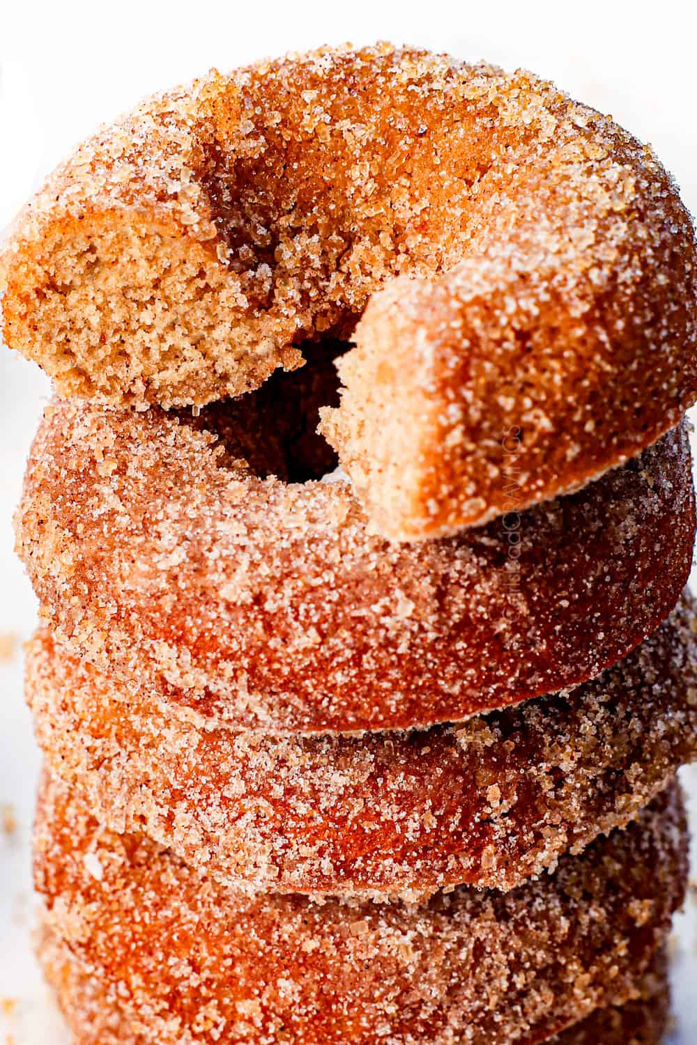 up close of easy apple cider donuts with a bite taken out, showing the cake-like texture inside