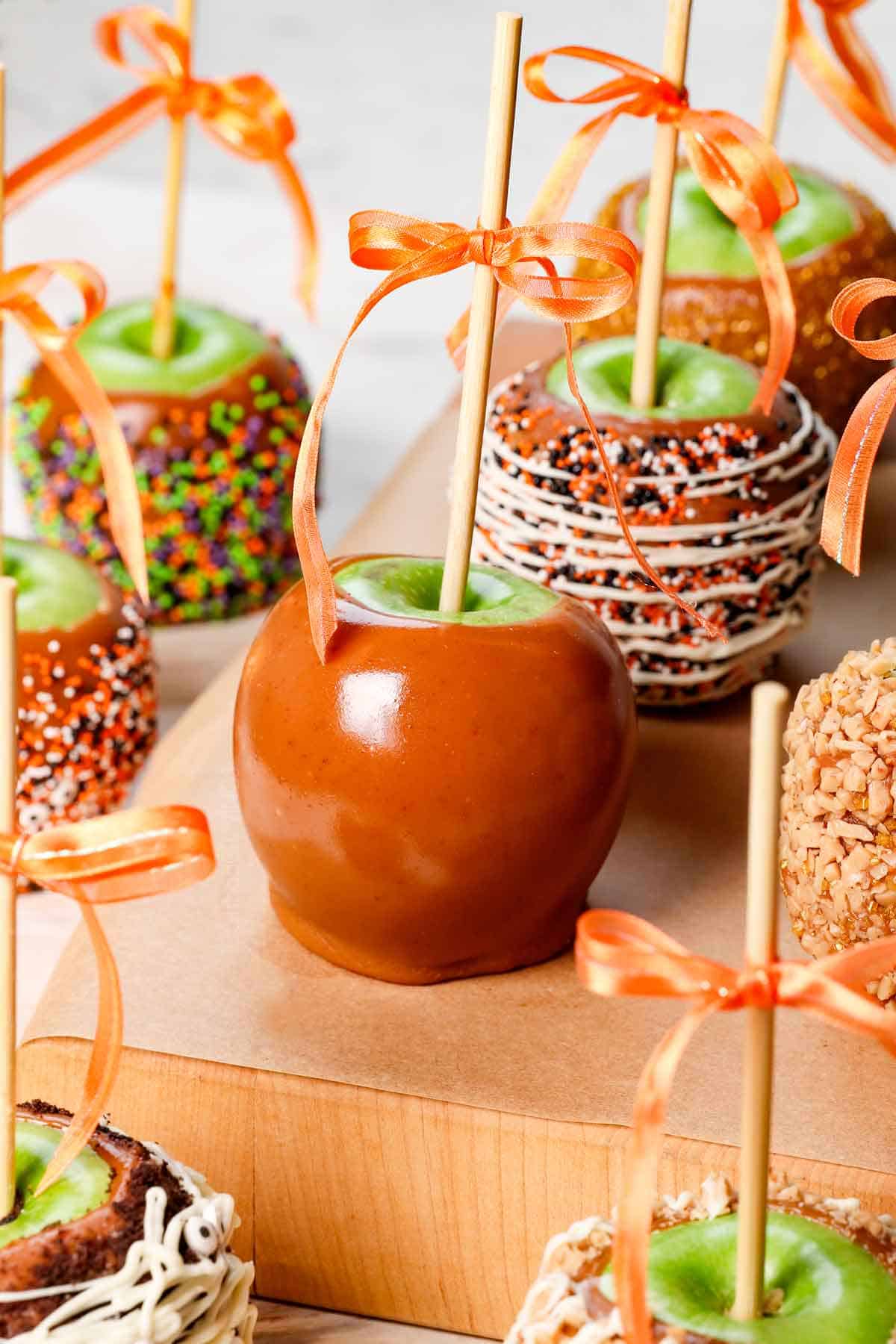 caramel apples recipe with thick caramel coating the apples lined a a parchment paper lined cutting board