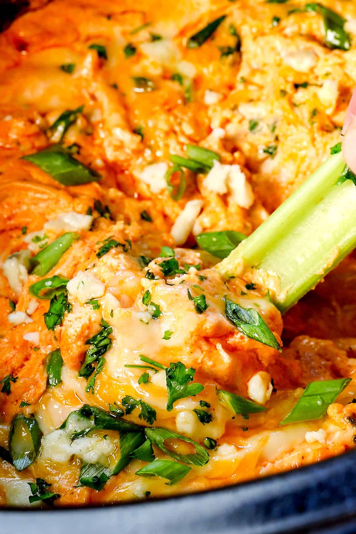 scooping buffalo chicken dip recipe crockpot with a celery stick