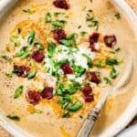 top view of loaded baked potato soup recipe in a bowl with sour cream, bacon, and green onions