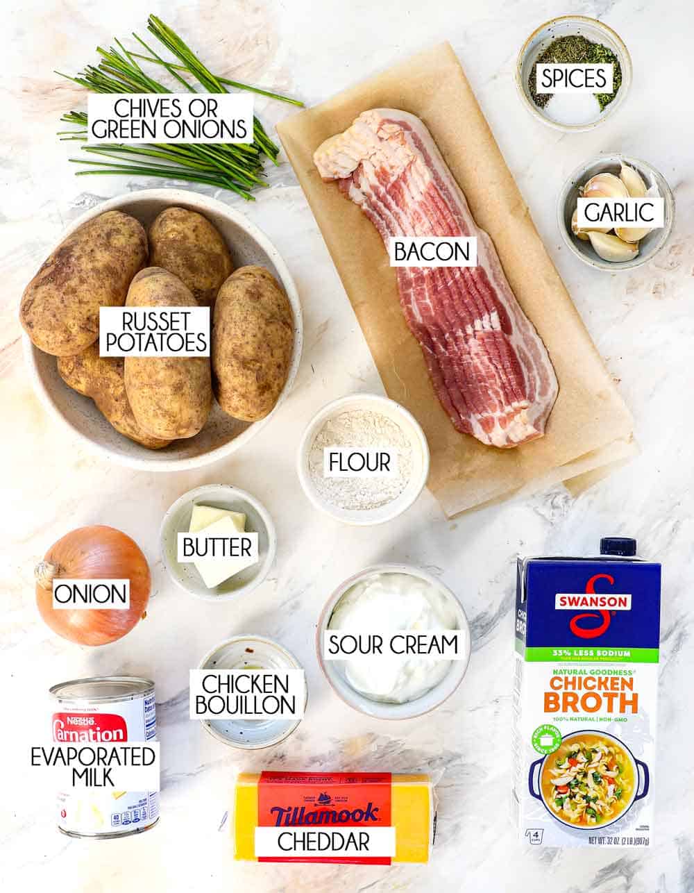 top view of loaded baked potato soup ingredients: potatoes, flour, onion, garlic, bacon, chicken broth, milk, cheese, green onions