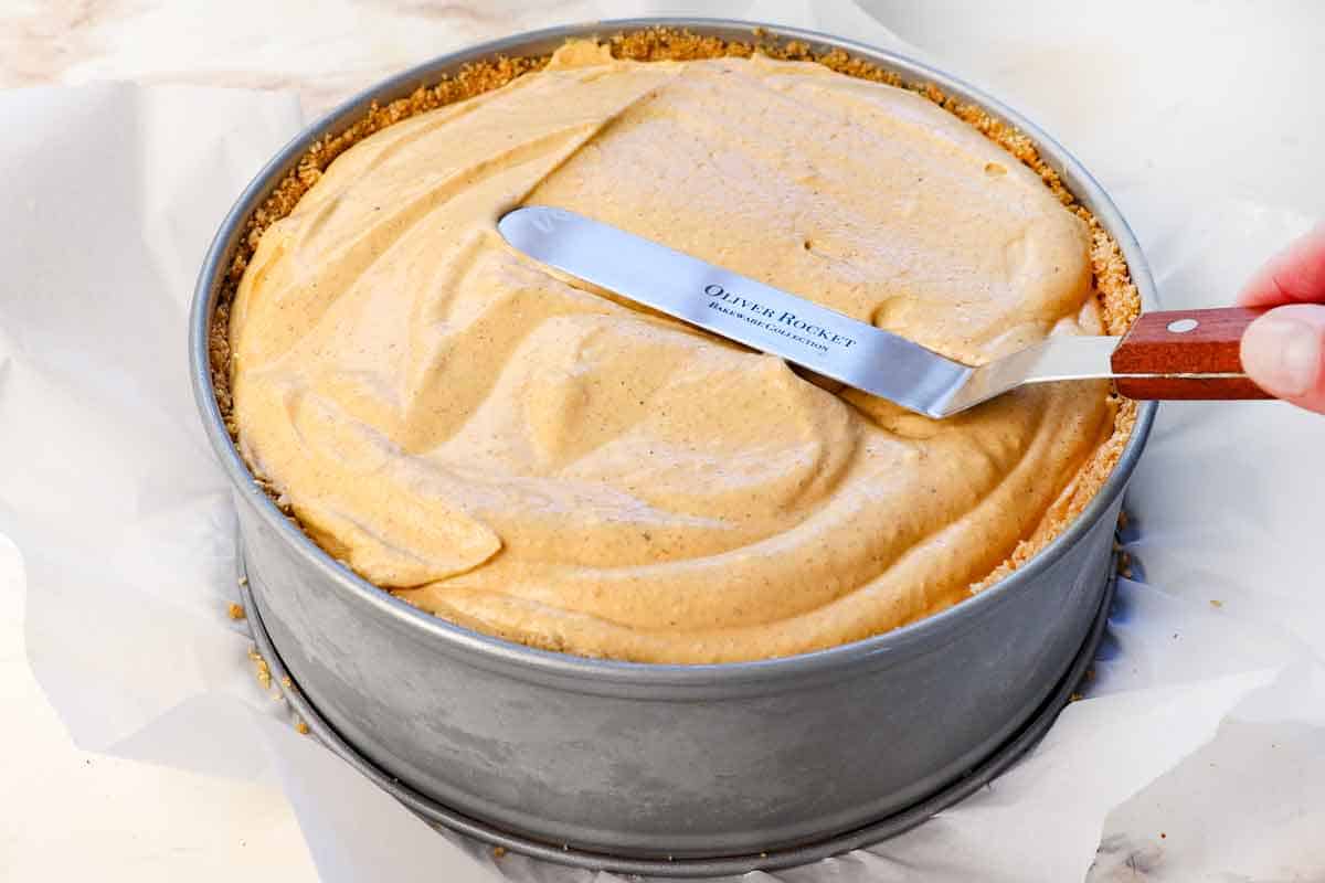 showing how to make No Bake Pumpkin Cheesecake by spreading the filling in the springform pan